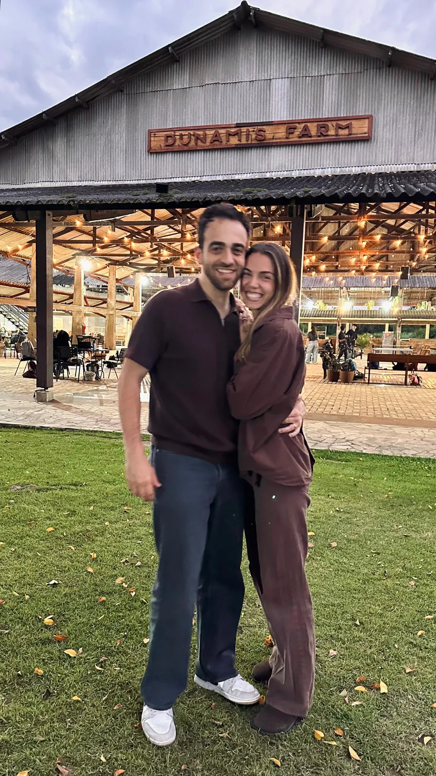 Henrique Krigner abraçado com a esposa, Letícia, ao ar livre no fim da tarde