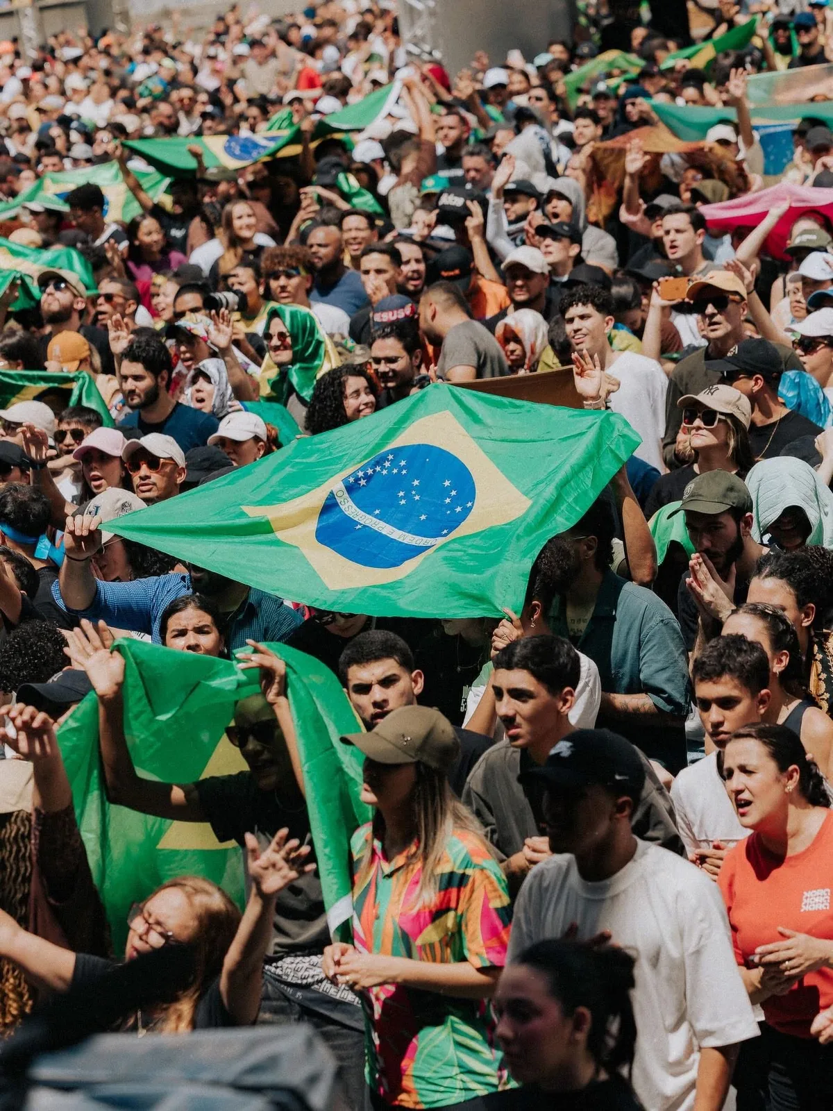 Multidão erguendo bandeiras do Brasil durante ato público em São Paulo